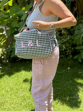 Load image into Gallery viewer, Person holding a black and white checkered bag stroller pouch with initials 'L&L' outdoors.